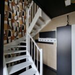 Escalier avec papier peint géométrique et garde-corps blanc