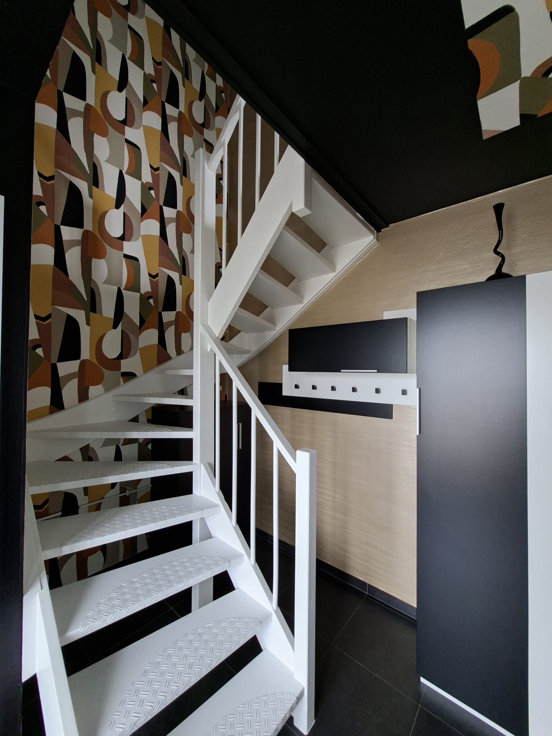 Escalier avec papier peint géométrique et garde-corps blanc