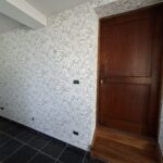Mur avec papier peint végétal clair et porte en bois