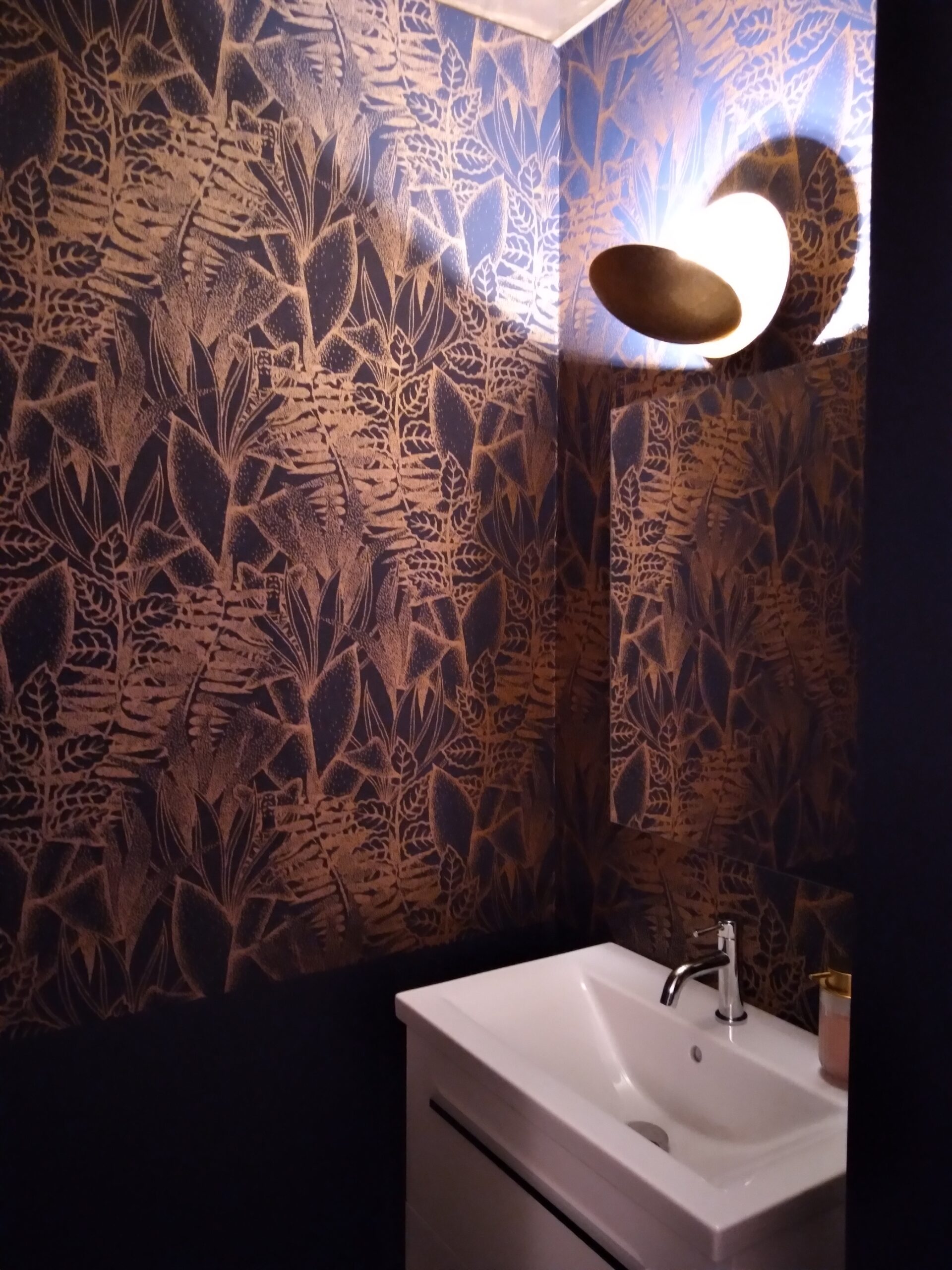Salle de bain avec papier peint tropical sombre et éclairage mural